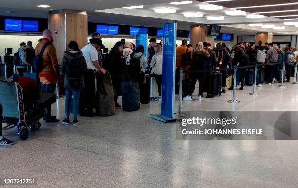 People queue in the departure hall of Terminal 7 at JFK airport on March 15, 2020 in New York City. - Chaos gripped major US airports Sunday as...