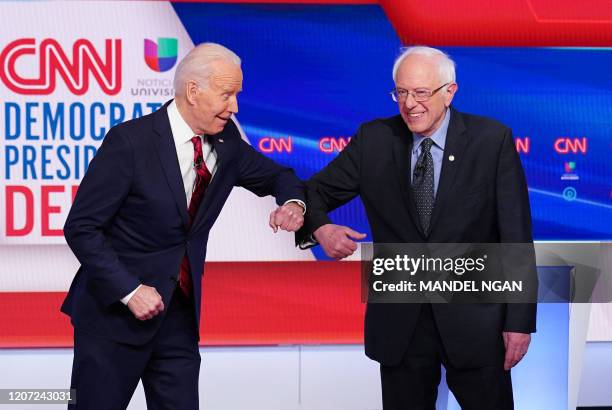 Democratic presidential hopefuls former US vice president Joe Biden and Senator Bernie Sanders greet each other with an elbow bump as they arrive for...
