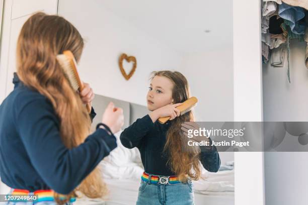 young girl brushing hair in mirror - man combing hair stock-fotos und bilder