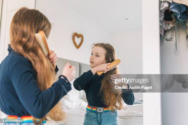 young girl brushing hair in mirror - combing foto e immagini stock