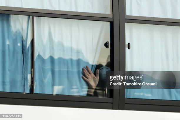 Man waves from a bus carrying passengers who disembarked the quarantined Diamond Princess cruise ship as he leaves the Daikoku Pier on February 19,...