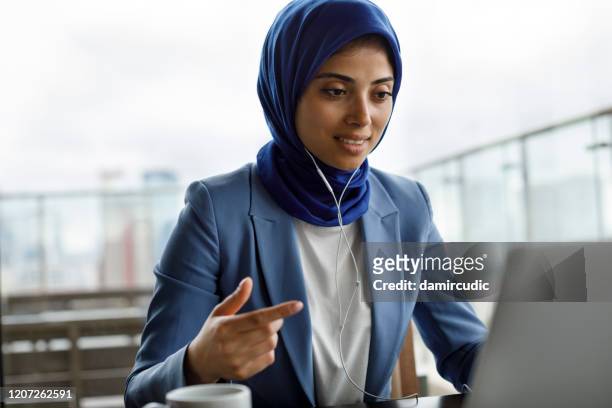 young woman with headphones working on laptop - west asia stock pictures, royalty-free photos & images