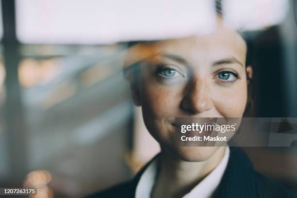 portrait of confident female entrepreneur seen through glass at workplace - glass reflection in office stock-fotos und bilder