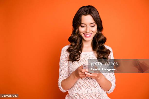 Portrait of positive cheerful girl use smartphone read social media news share information wear knitted outfit isolated over orange color background