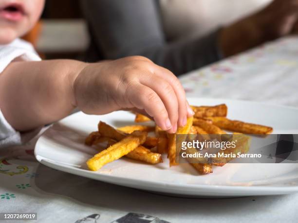 a baby's hand picking homemade chips from a plate - course meal stock pictures, royalty-free photos & images