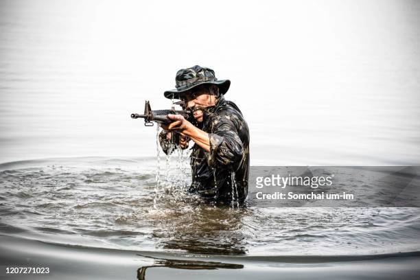 a soldier with gun is shooting in river battlefield - huntmaster stock pictures, royalty-free photos & images