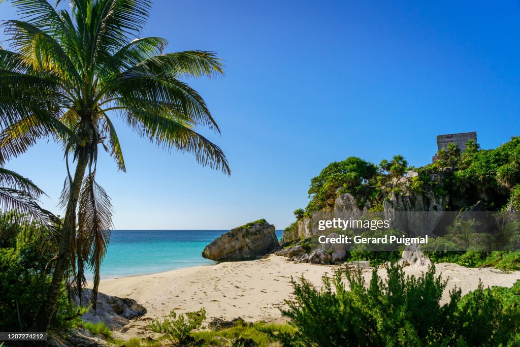 Beach with sea-side wall of El Castillo pyramid at the Ruins of Tulum, a pre-Columbian Mayan walled city in Yucatán Peninsula on the Caribbean Sea in the state of Quintana Roo, Mexico.