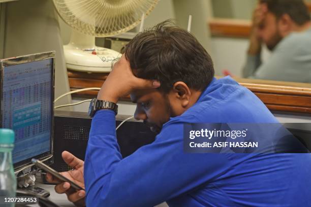 Stockbrokers react as they watch the latest share prices during a trading session at the Pakistan Stock Exchange in Karachi on March 16, 2020.