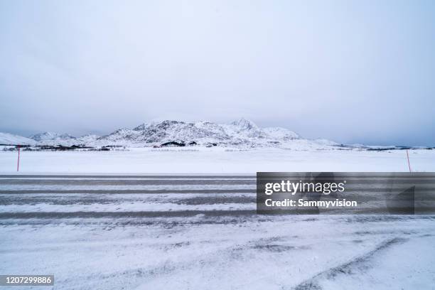 icy road against snowcapped mountain - snow parking lot stock pictures, royalty-free photos & images