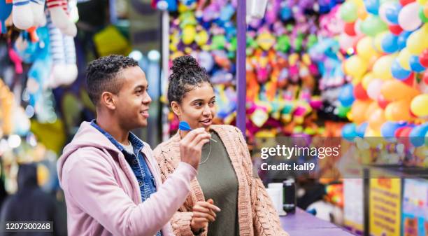 young african-american couple playing carnival game - fairground stall stock pictures, royalty-free photos & images