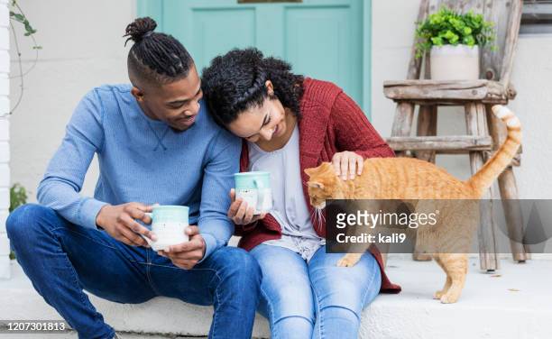 coppia afroamericana sui gradini del portico, gatto accarezzante - pets foto e immagini stock
