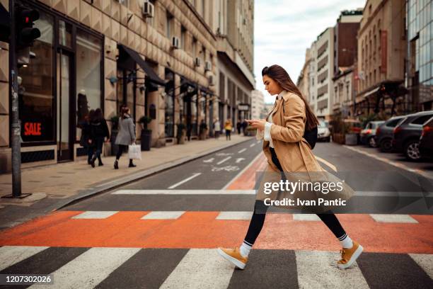 bella donna che attraversa la strada - attraversare foto e immagini stock