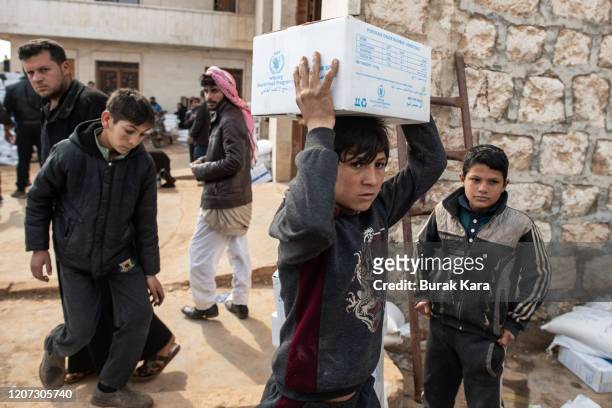 Displaced Syrian boy carries a box of humanitarian aid supplied by an NGO on February 19, 2020 in Idlib, Syria. Turkey’s President Recep Tayyip...