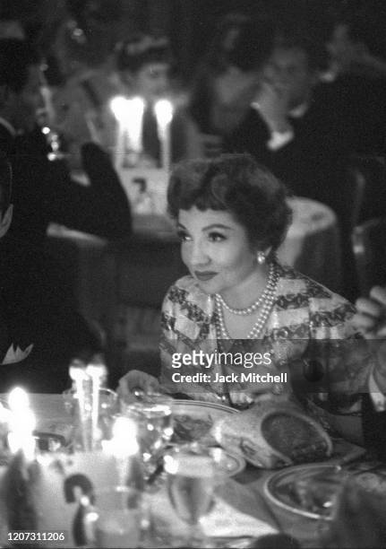 Actress Claudette Colbert sits at a table during the Plaza Hotel Halloween Party, October 31, 1959.