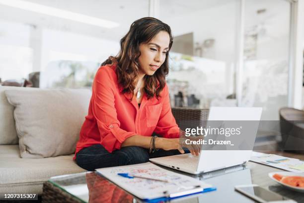 mature latin american businesswoman working from home - using laptop stock pictures, royalty-free photos & images