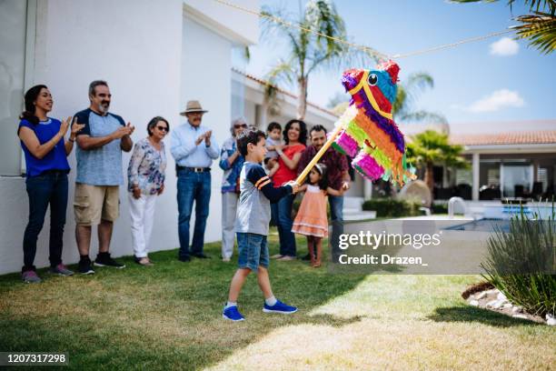 la familia apoya a la joven latina cuando golpea pi-ata - piñata fotografías e imágenes de stock