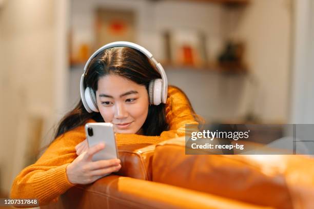 elegante joven escuchando música en casa - headphones asian fotografías e imágenes de stock