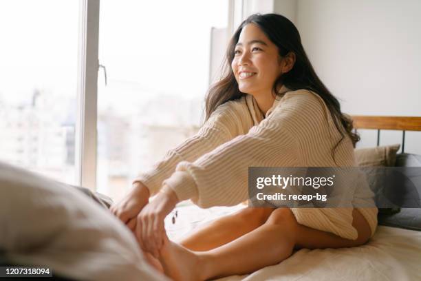 jonge vrouw die haar benen voor de dag op haar bed uitrekt - beautiful asian legs stockfoto's en -beelden