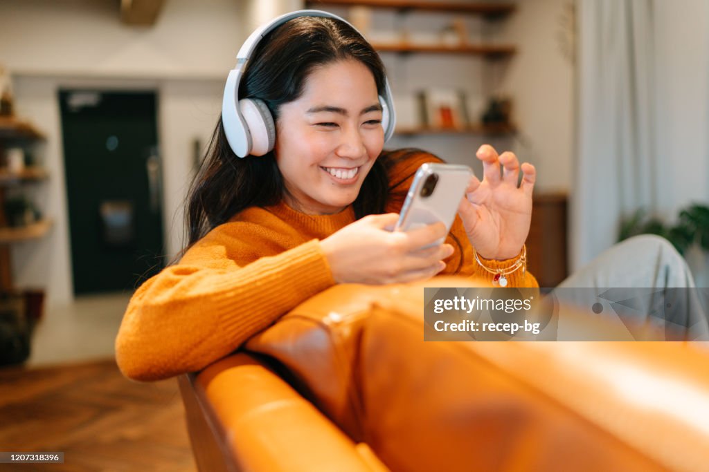 Stilvolle junge Frau, die zu Hause Musik hört
