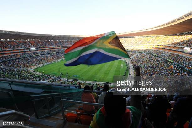 Football fan waves the South African flag at Soccer City in Soweto on May 22, 2010 during a local football match to inaugurate the opening of Soccer...