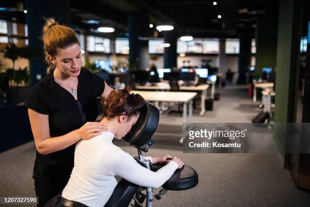 giovane donna d'affari esausta che si gode il massaggio al collo dopo una lunga giornata di lavoro in ufficio - massaggiare foto e immagini stock