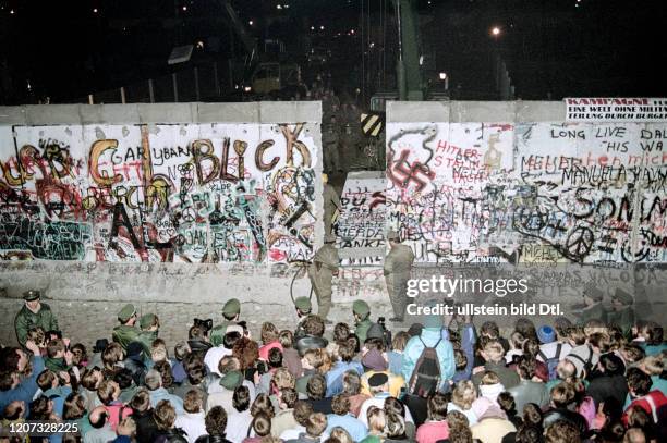 Fall of the Berlin Wall: demolition of the Wall at Potsdamer Platz, watched by a crowd of people on the West Berlin side- Vintage property of...