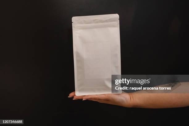 white hand holding a white bag of coffee - white label stock pictures, royalty-free photos & images