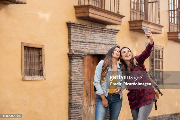 amici latini di circa 25 anni che viaggiano attraverso la città di bogotà si fermano per un momento per scattare un selfie - bogota foto e immagini stock