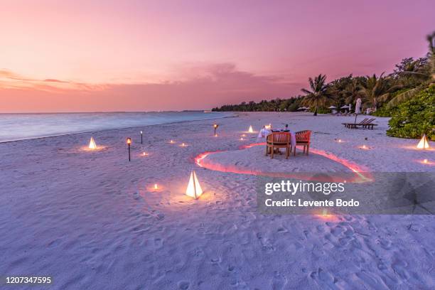 luxury honeymoon destination, romantic dinner with candles heart on the calm sand beach landscape. luxury wedding anniversary dinner - attività romantica foto e immagini stock