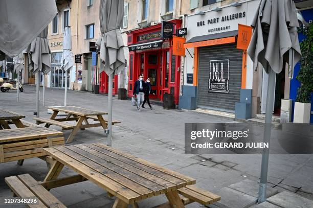 Couple wearing face masks walk along closed bars and restaurants next to the Vieux-Port in Marseille, southern France, on March 16 after all...