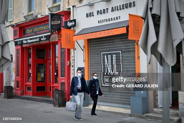 Couple wearing face masks walk along closed bars and restaurants next to the Vieux-Port in Marseille, southern France, on March 16 after all...
