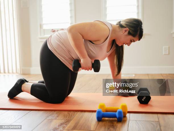 woman using exercise weights in a home - heavy equipment stock pictures, royalty-free photos & images