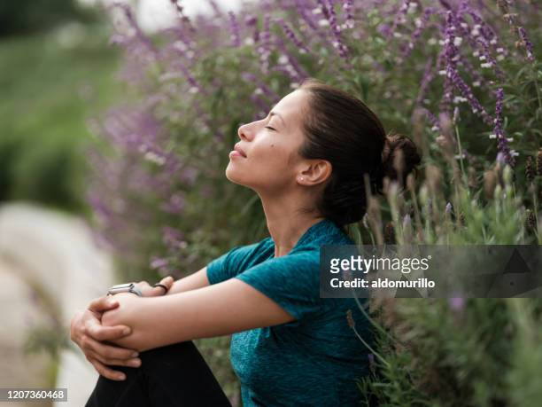 latijnse vrouw die naast bloemen ontspant - meditating stockfoto's en -beelden