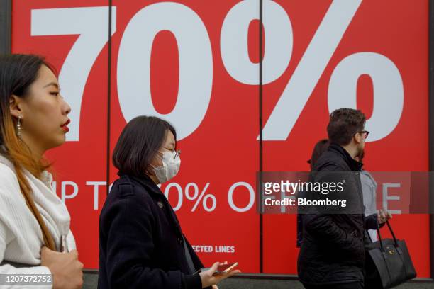 Pedestrian wearing a protective face mask passes sale signage at fashion store on Oxford Street in central London, U.K., on Monday, March 16, 2020....