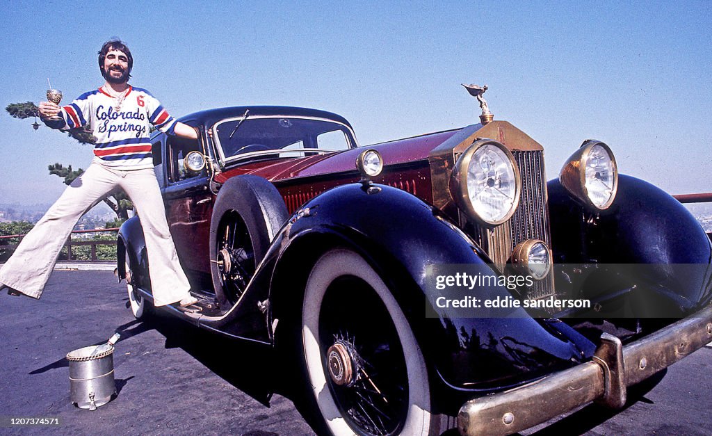 Keith Moon, The Who's Celebrated Drummer Standing On The Running Board Of His Classic Rolls-Royce Car On Mulholland Drive In The Hollywood Hills In Los Angeles, California, June 1976.