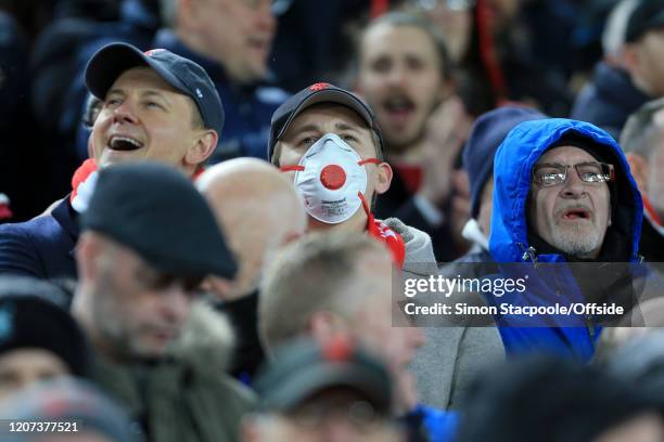 Fan wears a face mask in light of the growing Coronavirus concerns during the UEFA Champions League round of 16 second leg match between Liverpool FC...