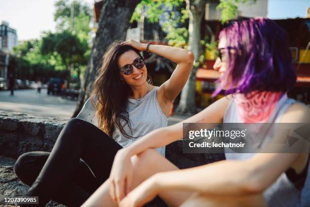 zwei mädchen sitzen und plaudern auf der straße - purple hair stock-fotos und bilder