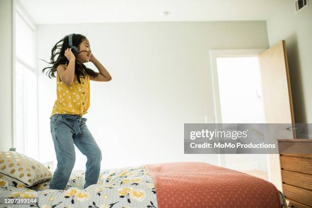 young girl (6 yrs) using headphones and tablet at home - bright bedroom stockfoto's en -beelden