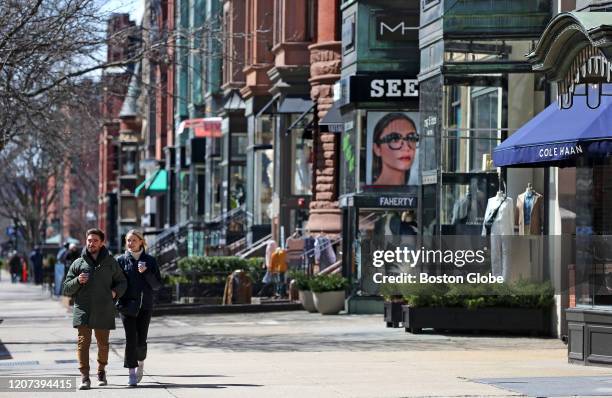 Couple walks down Newbury Street in Boston, a street with many retail stores, on March 16, 2020. Governor Charlie Baker ordered restaurants and bars...