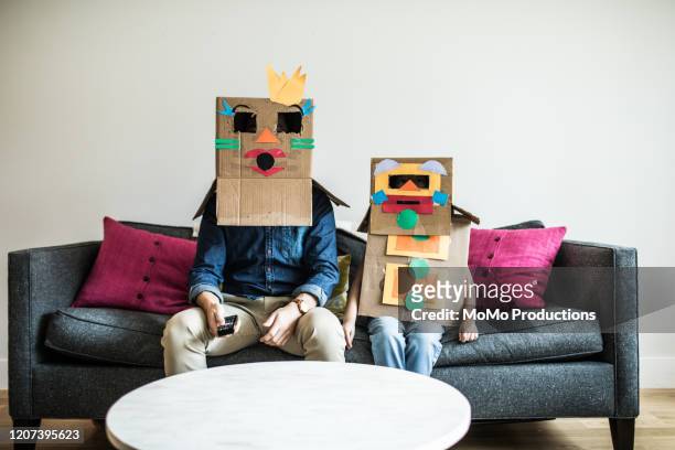 father and daughter wearing robot costumes watching television - arts culture and entertainment stock-fotos und bilder