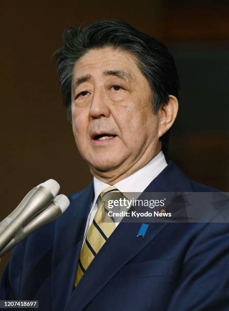 Japanese Prime Minister Shinzo Abe speaks to reporters at his office in Tokyo in the small hours of March 17 after participating in a videoconference...