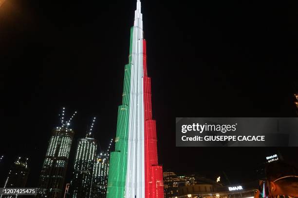 Picture taken on March 16, 2020 shows Dubai's Burj Khalifa lit up in the colours of the Italian flag and "We are with you" message as a sign of...