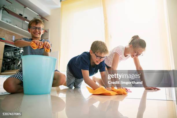 thee kids cleaning floor in the kitchen - family housework stock pictures, royalty-free photos & images