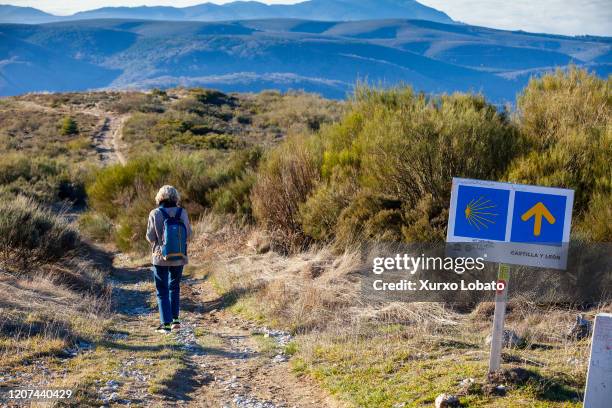 Pilgrim on the road to Santiago walks towards El Bierzo following the yellow arrow sign,as seen January 6 El Acebo, Castilla y Leon,Spain.