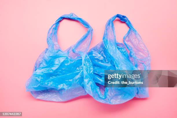 high angle view of a blue plastic bag on pink colored background - plastic bag stock-fotos und bilder