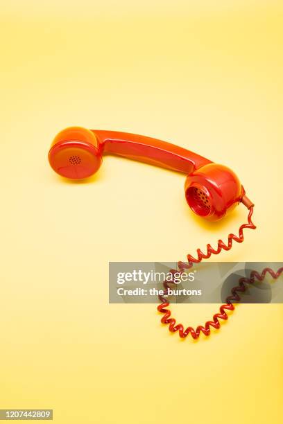 high angle view of a red old-fashioned telephone receiver on yellow background - wire binding stock pictures, royalty-free photos & images