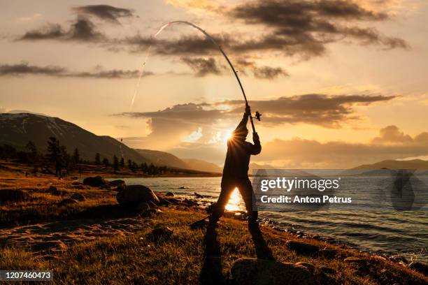 silhouette of a fisherman at sunset on a lake - rod stock pictures, royalty-free photos & images