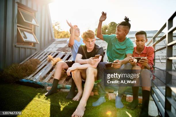 boys hangout on a terrace - teenage boy playing playstation stock pictures, royalty-free photos & images