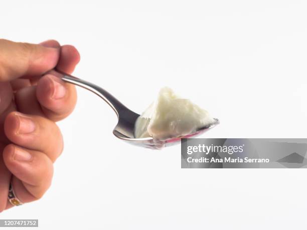 a spoon with yogurt - spoon in hand stock-fotos und bilder