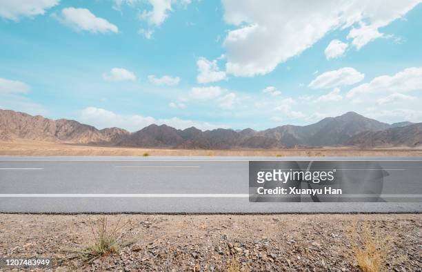 asphalt road in arid area - wüstenstraße stock-fotos und bilder
